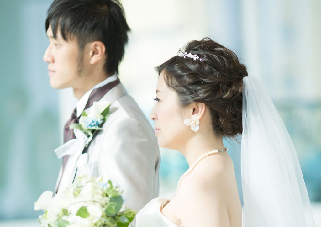 結婚式で並んで立つ新郎新婦の横顔を捉えたウエディングフォト