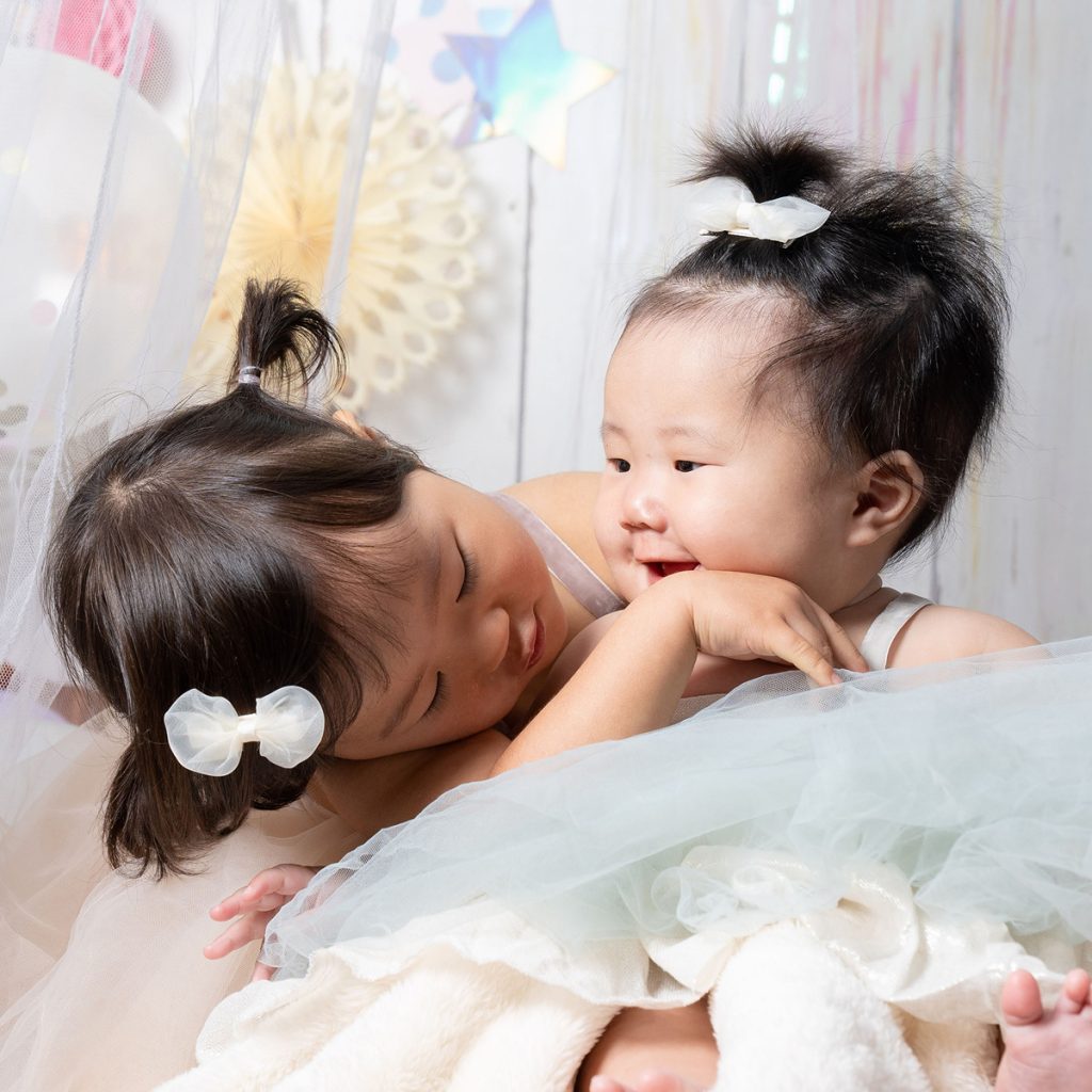 寄り添う赤ちゃんの穏やかな表情を撮影した姉妹フォト