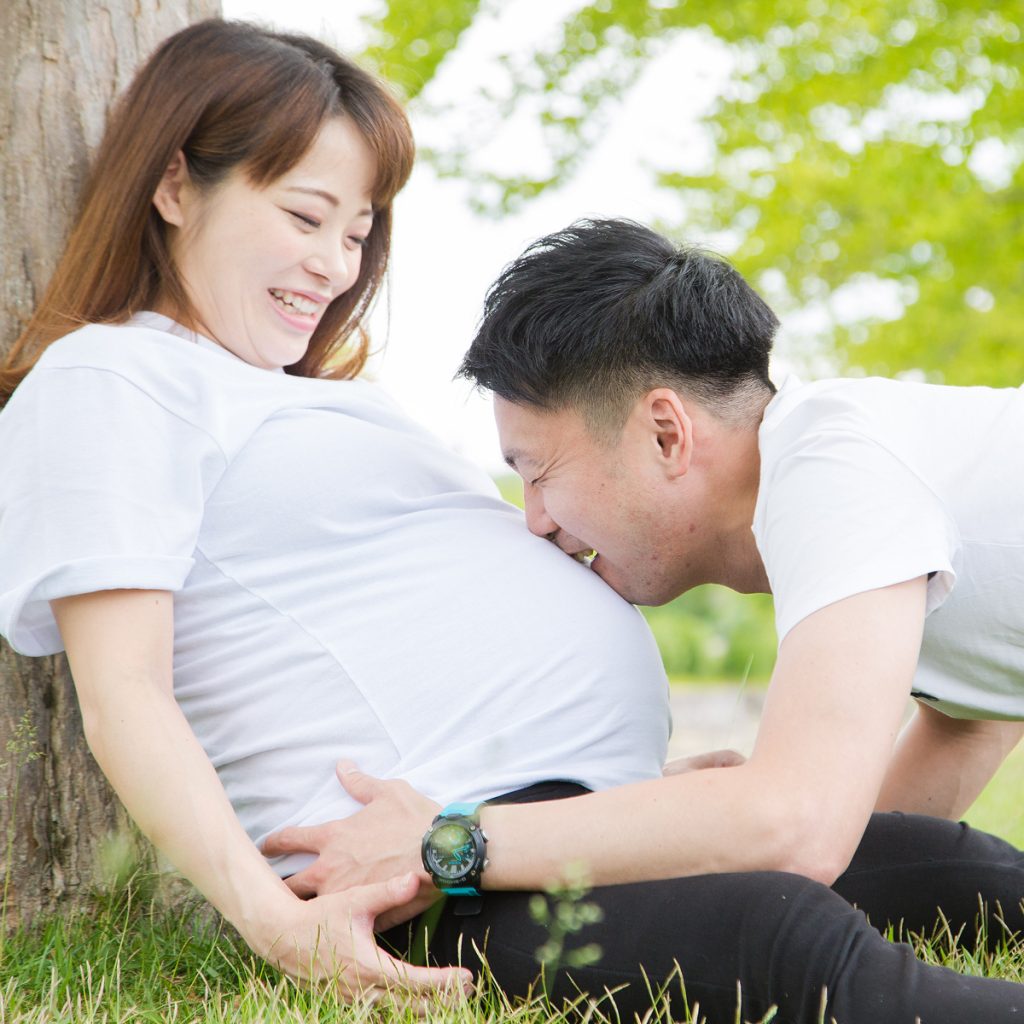 屋外でお腹に寄り添うご夫婦のナチュラルなマタニティフォト