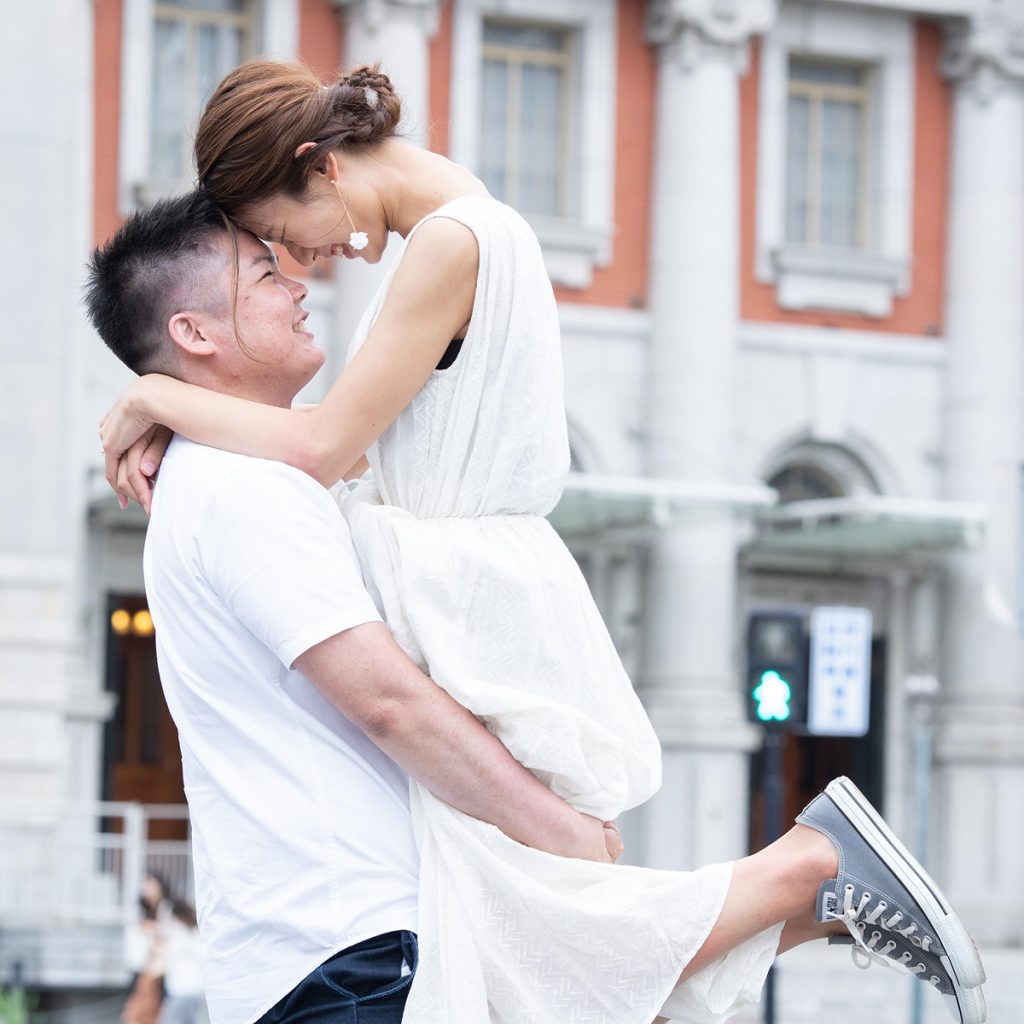 街中で抱き上げる新郎新婦のカジュアルな前撮り写真