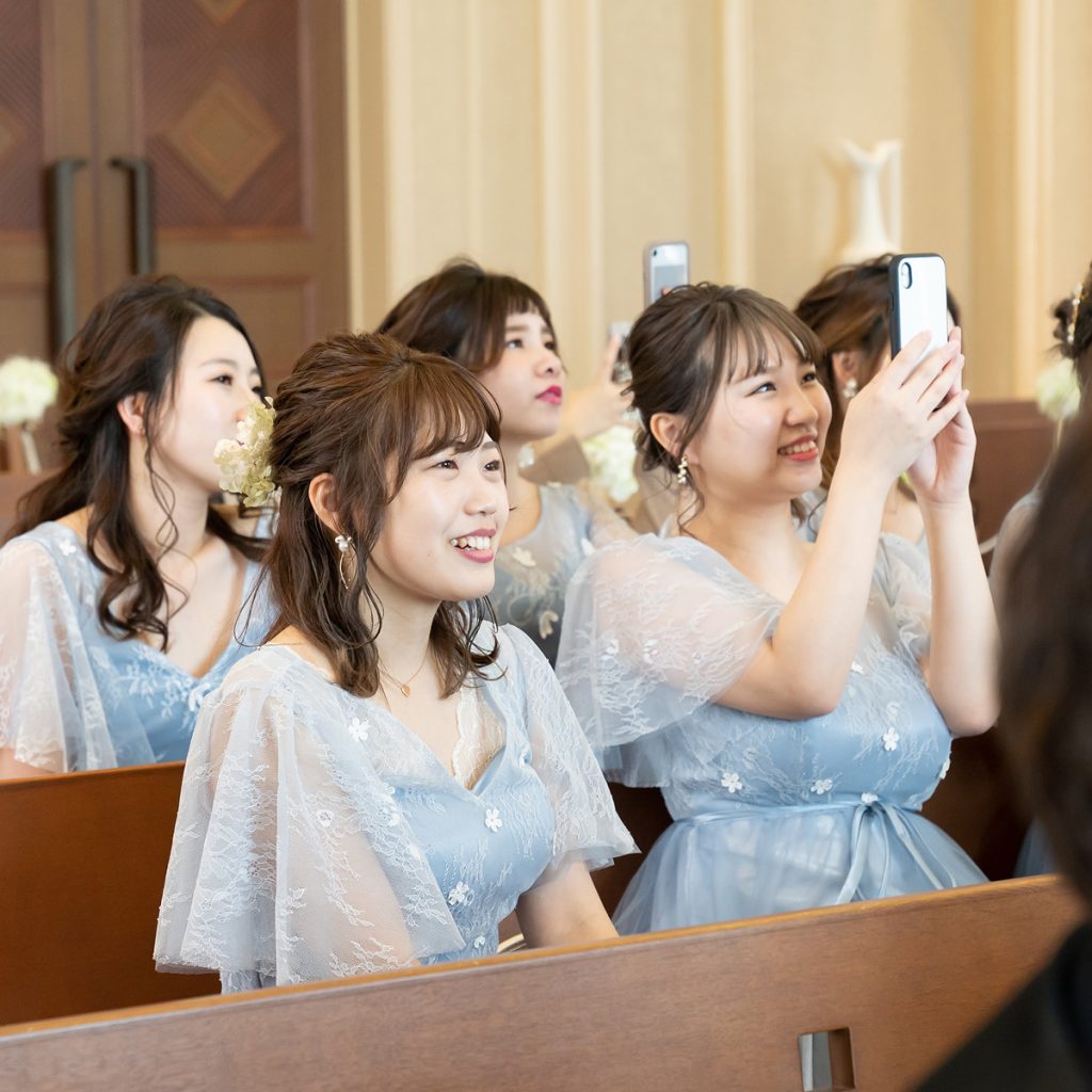 結婚式でスマートフォンを構えて祝福するゲストの様子

