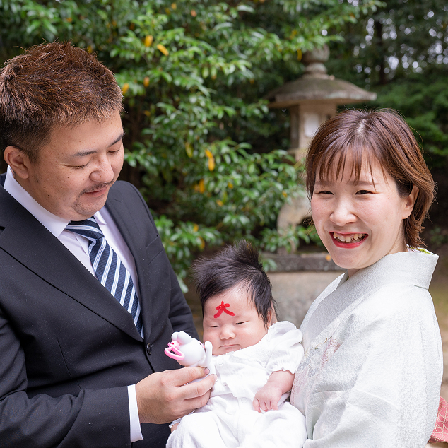 お宮参りで赤ちゃんを囲むご両親の記念写真
