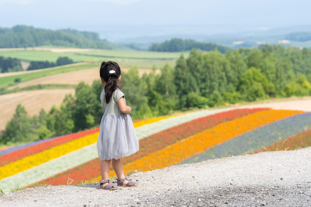北海道の花畑を見渡す女の子のロケーション撮影