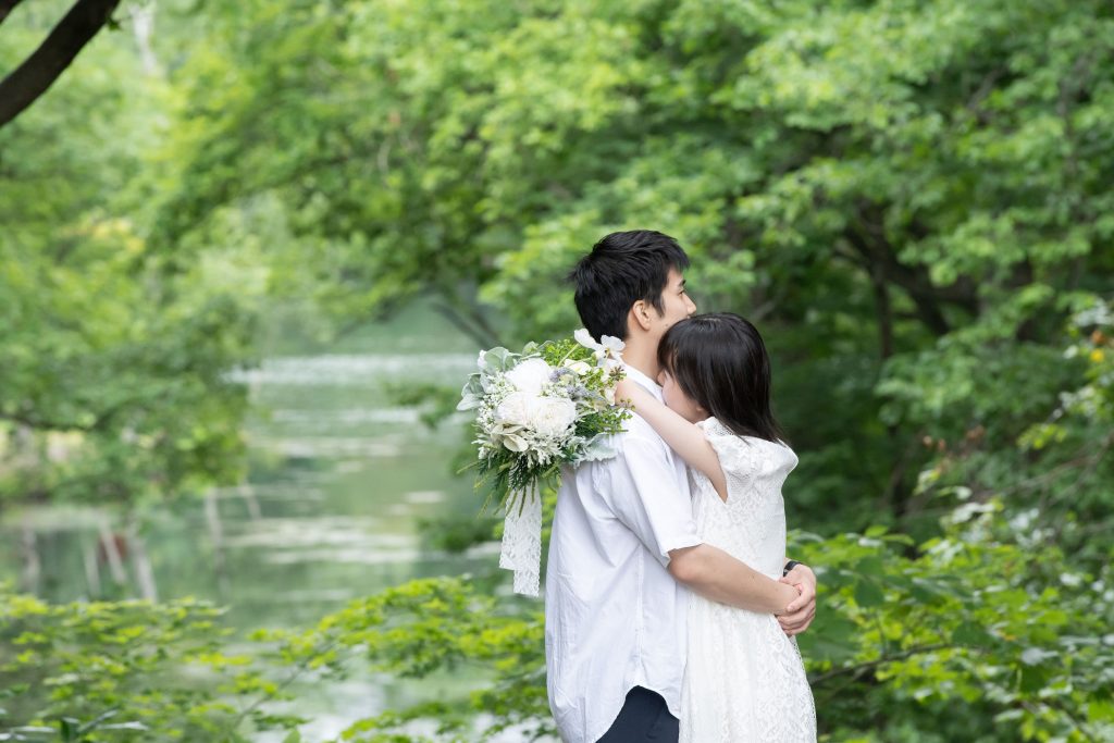 鳥沼公園の湖の前で抱き合うカップルの写真