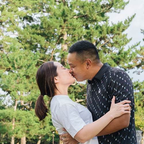 A romantic couple sharing a kiss during their anniversary photo shoot in a scenic Japanese location.