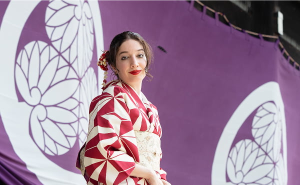 An elegant portrait of a traveler at a sacred heritage site in Kyoto, with beautiful purple drapery and ancient architecture creating a serene atmosphere.